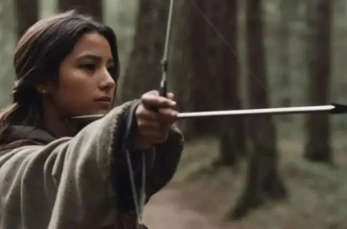 a young woman in medieval cloak draws her bow in a forest