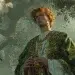 Aengus Óg, the Celtic god of love and youth, from Irish mythology, standing in a misty green glade appears youthful and radiant, with tousled auburn hair wearing a flowing green and gold tunic