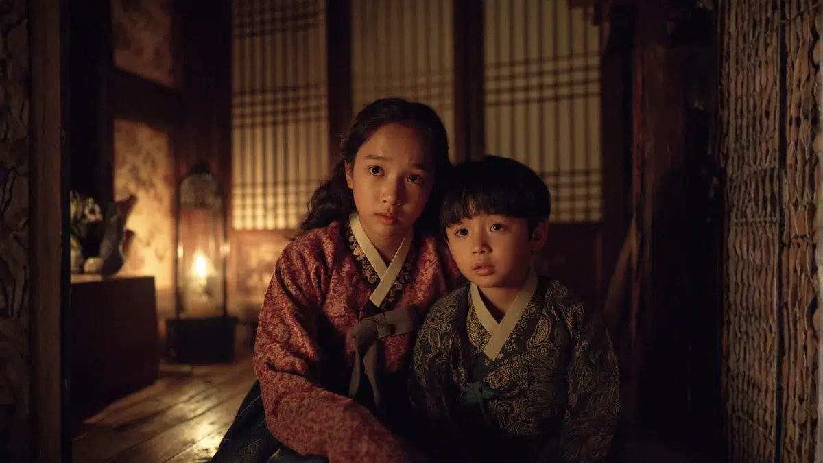 a young Korean girl and boy huddle together