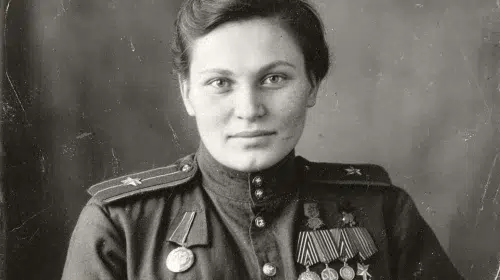 Black and white 1940s Soviet military portrait of a decorated female sniper in uniform, formal studio setting, WWII era Red Army officer, short parted hair neatly combed back